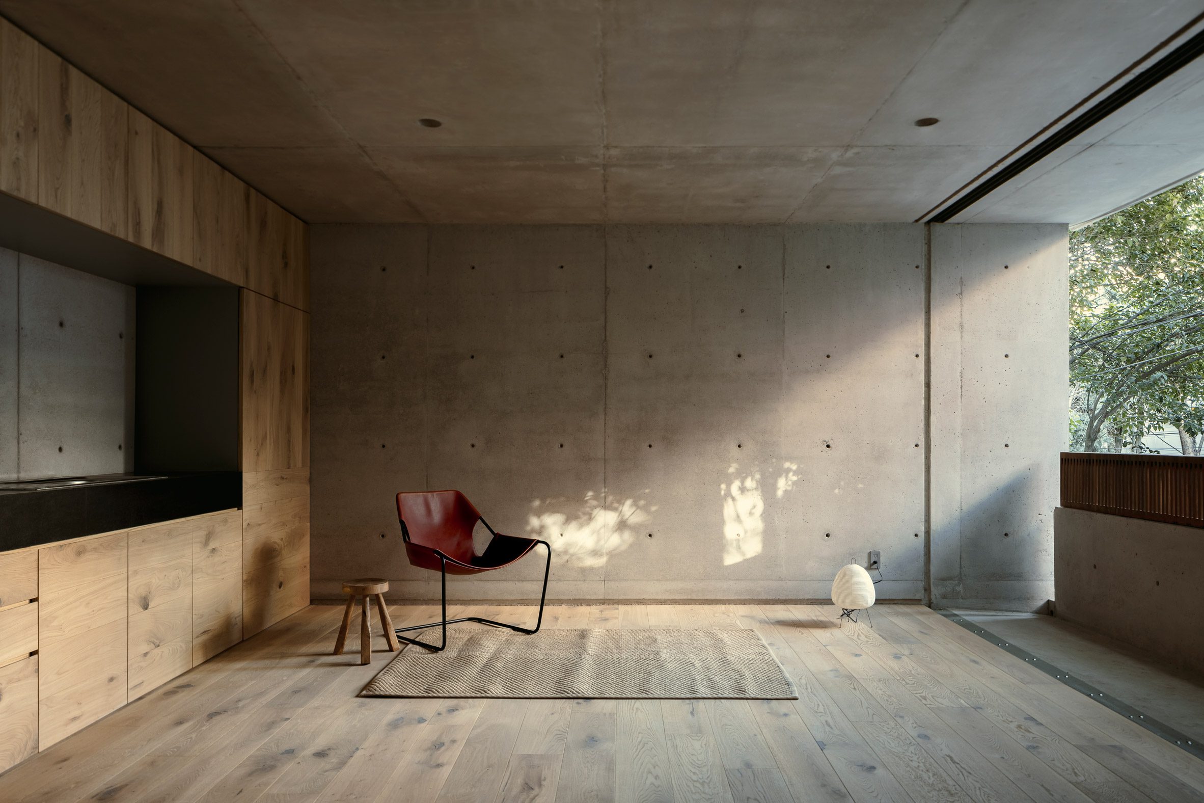 Concrete living room with chair, light and stool