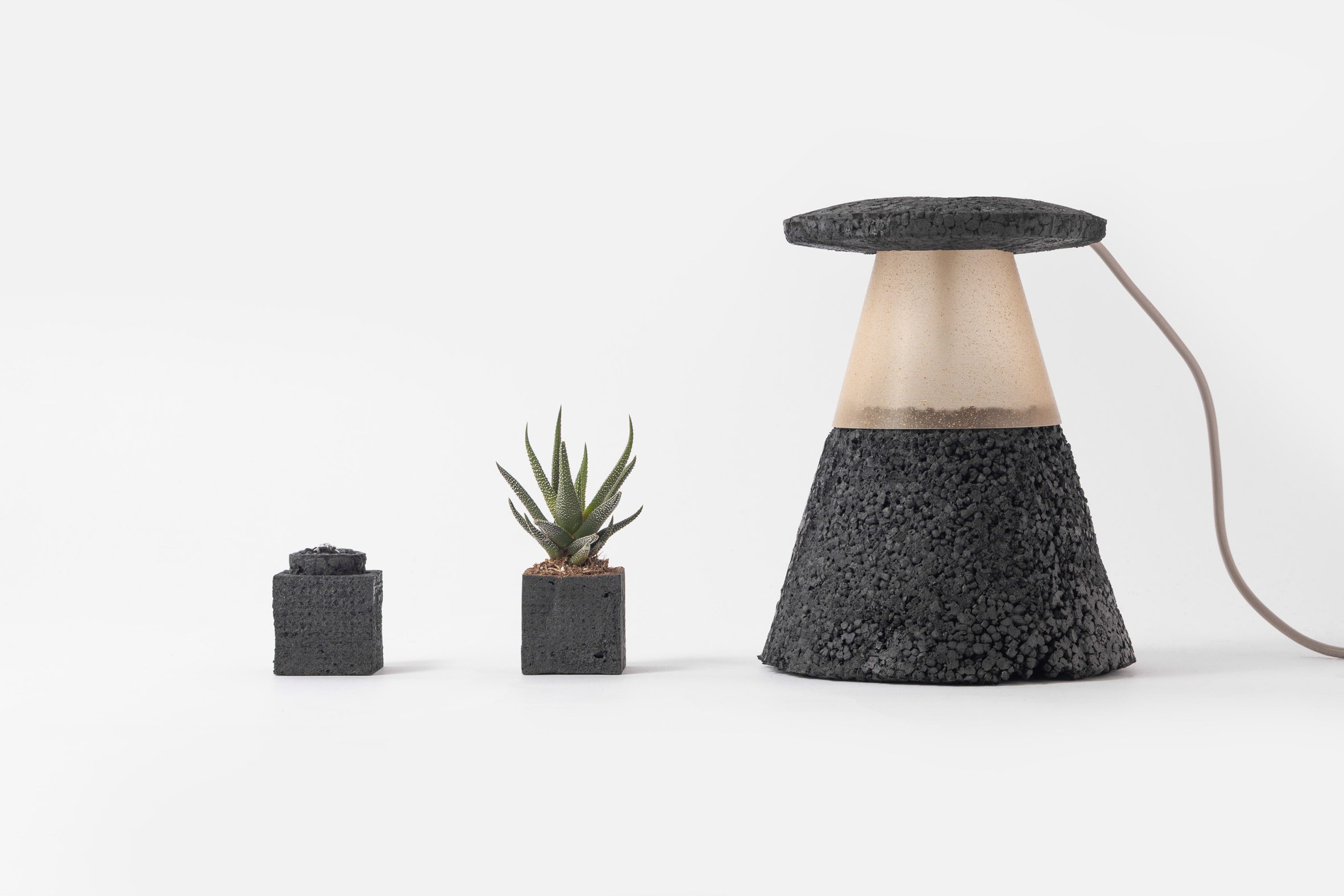 Photo of the Carbon Cell collaboration with Morrama showing a ring box, small plant pot and table lamp all made from black-coloured rigid foam packaging material